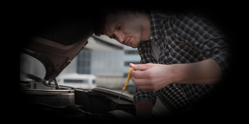 Mann überprüft den Ölstand am Peilstab im Motorraum